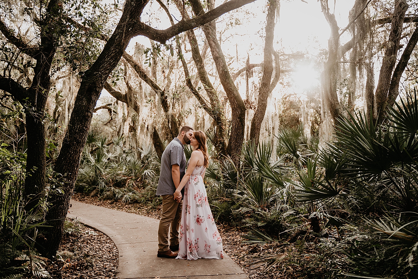 Wide shot of couple holding each other in bright forest Delray Oaks Engagement Photography captured by South Florida Engagement Photographer Krystal Capone Photography