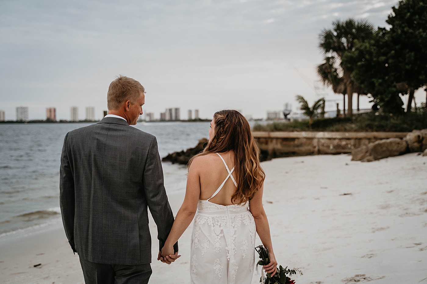 Bride and Groom looking at the ocean holding hands South Florida Elopement Photography captured by Krystal Capone Photography