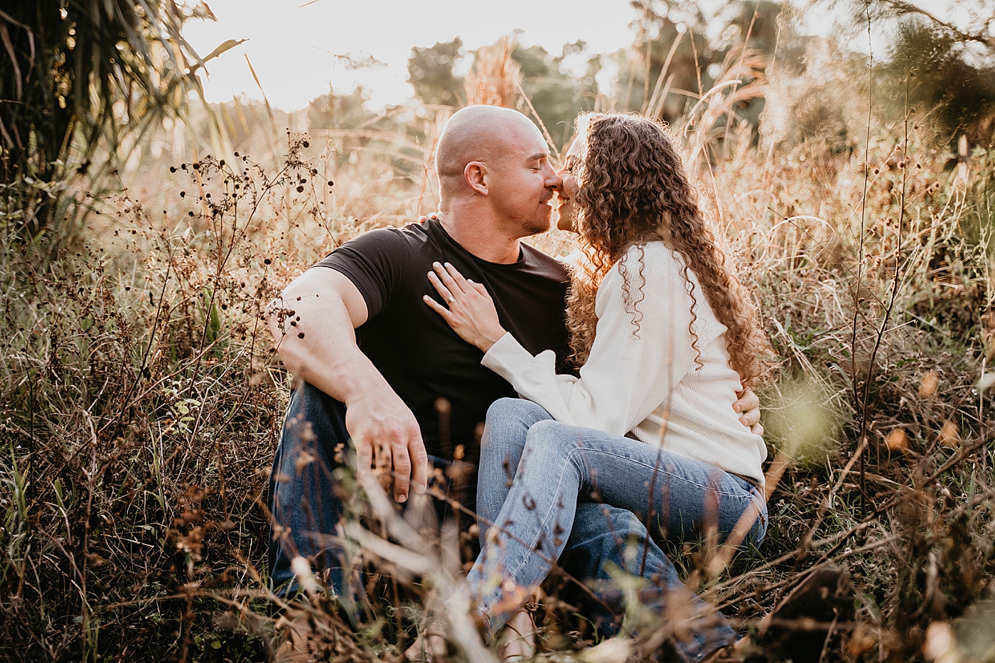 Couple sitting on field and about to kiss Romantic Riverbend Park Engagement Photography captured by South Florida Photographer Krystal Capone Photography