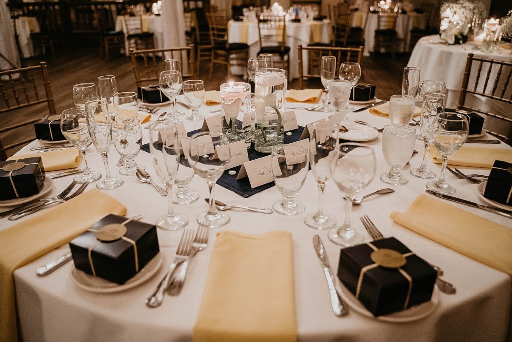 Reception table with glasses and black gift boxes on plates with candle centerpiece 94th Aero Squadron Miami Wedding Photography captured by South Florida Engagement Photographer Krystal Capone Photography 