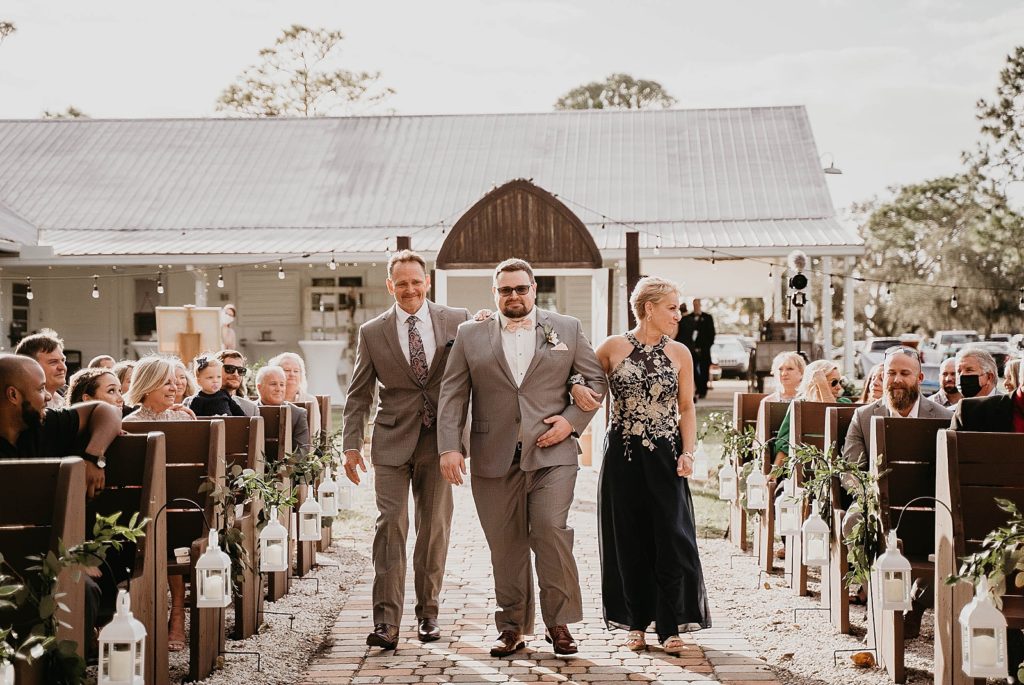 Groom entering Ceremony with father and mother walking down the aisle arm in arm Ever After Farms Wedding Photography captured by South Florida Wedding Photographer Krystal Capone Photography 