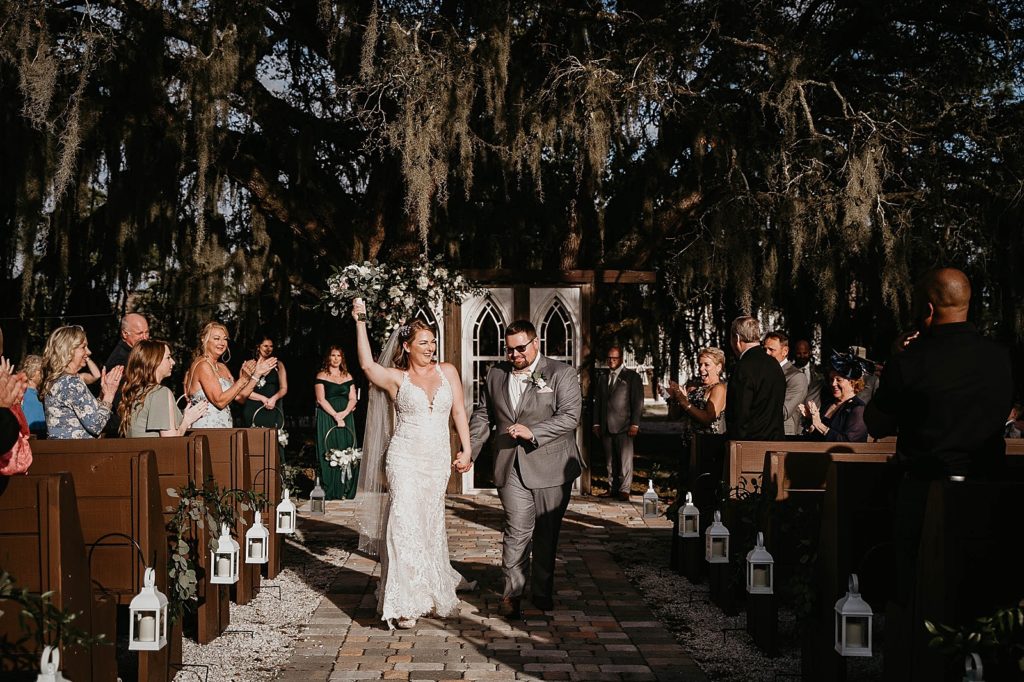 Bride and Groom exiting ceremony with Bride raising her bouquet up in the air Ever After Farms Wedding Photography captured by South Florida Wedding Photographer Krystal Capone Photography 