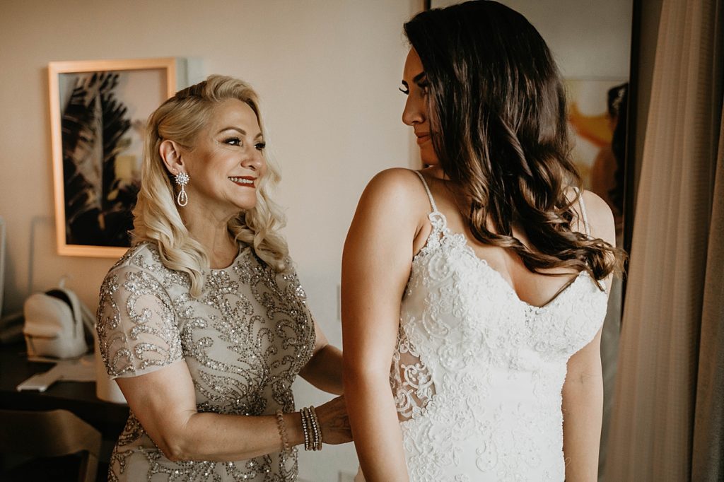 Bride getting ready getting help buttoning dress Hawks Cay Resort Wedding Photography captured by South Florida Wedding Photographer Krystal Capone Photography 