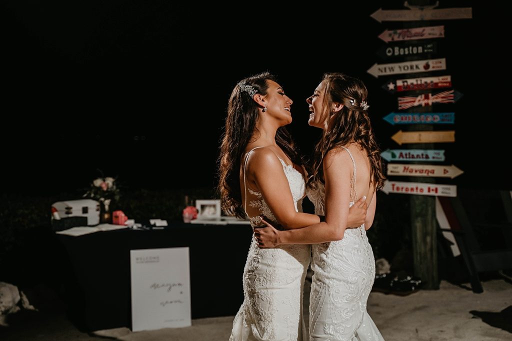 Brides holding each other close laughing right by wedding table Hawks Cay Resort Wedding Photography captured by South Florida Wedding Photographer Krystal Capone Photography