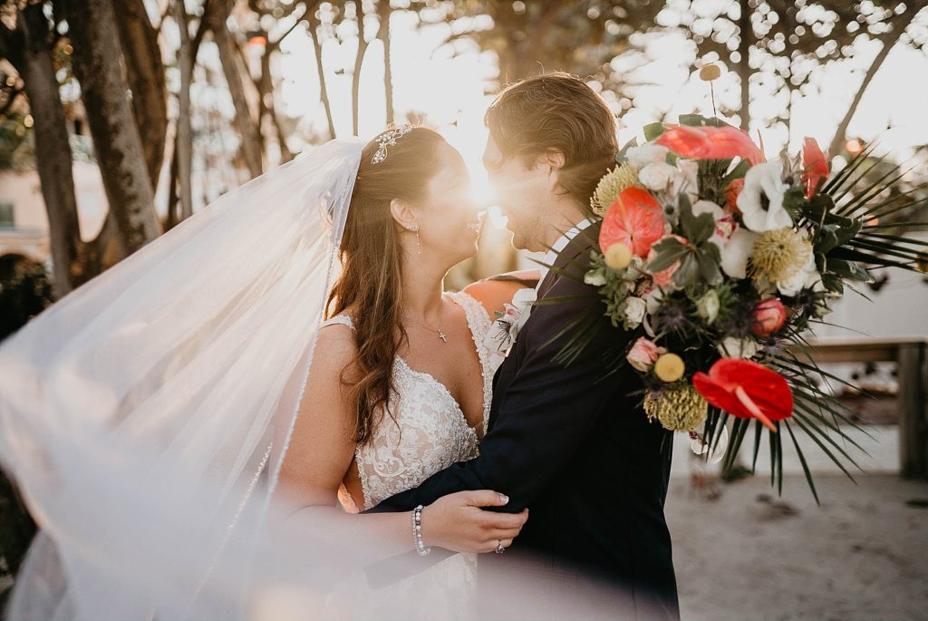 Bride and Groom holding each other with solar lens flair blocking their face Jupiter Beach Resort Wedding Photography captured by South Florida Wedding Photographer Krystal Capone Photography  
