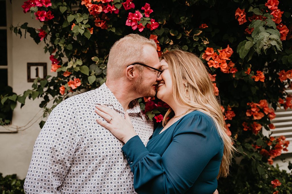 Couple just about to kiss in front of bright flower shrub Worth Ave Palm Beach Engagement Photography captured by South Florida Engagement Photographer Krystal Capone Photography