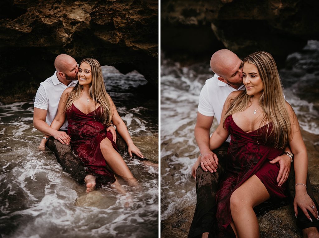 Man kissing woman sitting on his lap in ocean water
