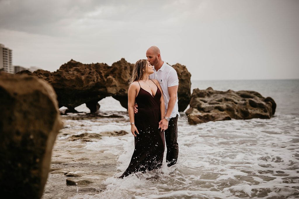 Man kissing lady on her forehead in the ocean water