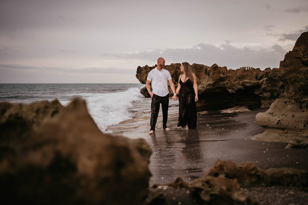 Couple holding hands on the shoreline of the beach