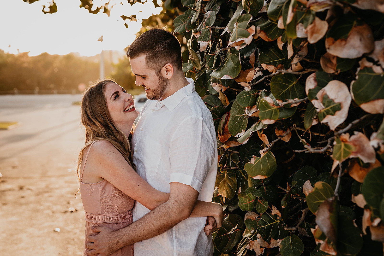 Couple holding each other by green hedge