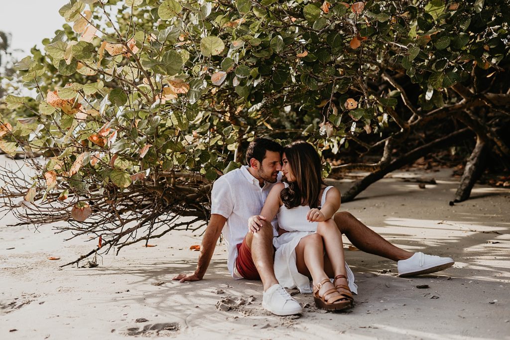 Couple sitting by tree branches and touching their noses