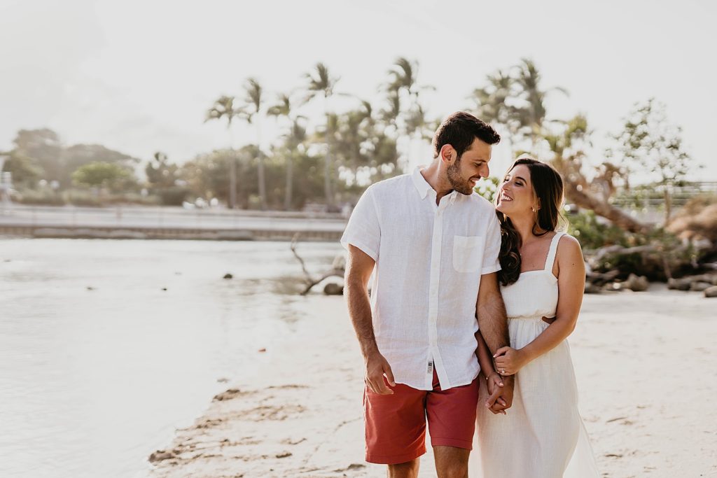 Couple holding hands and walking by the water on the beach