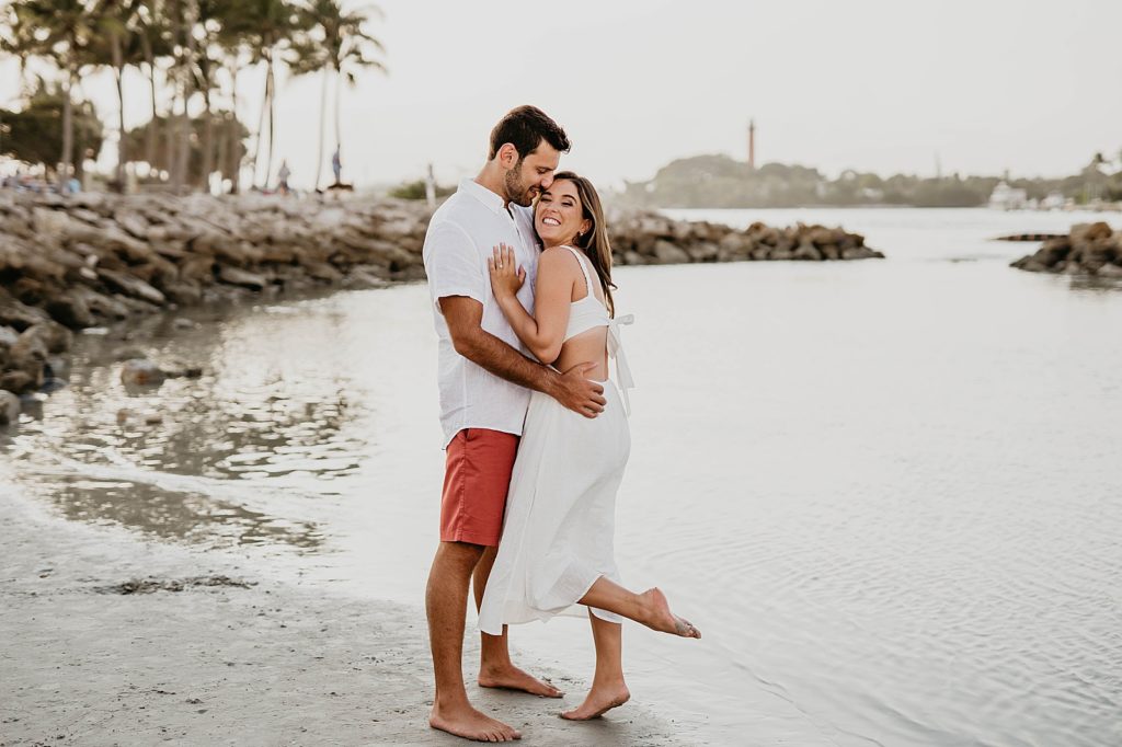Couple holding each other close by the shoreline