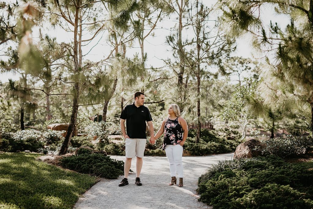 Couple holding hands and looking at each other on sidewalk