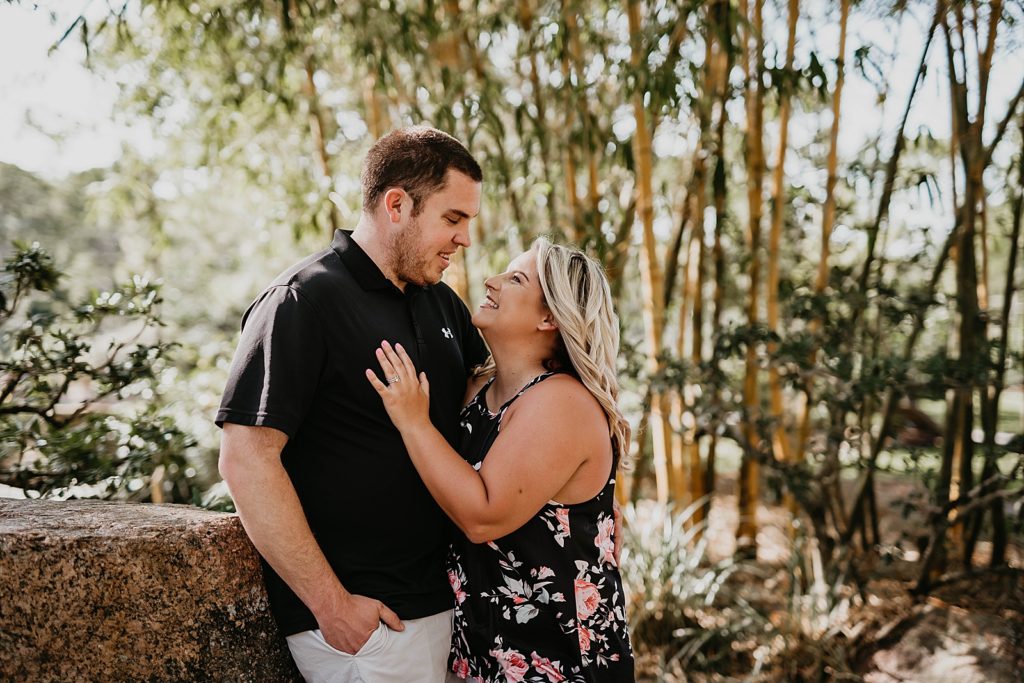 Couple holding each other close by forest rock