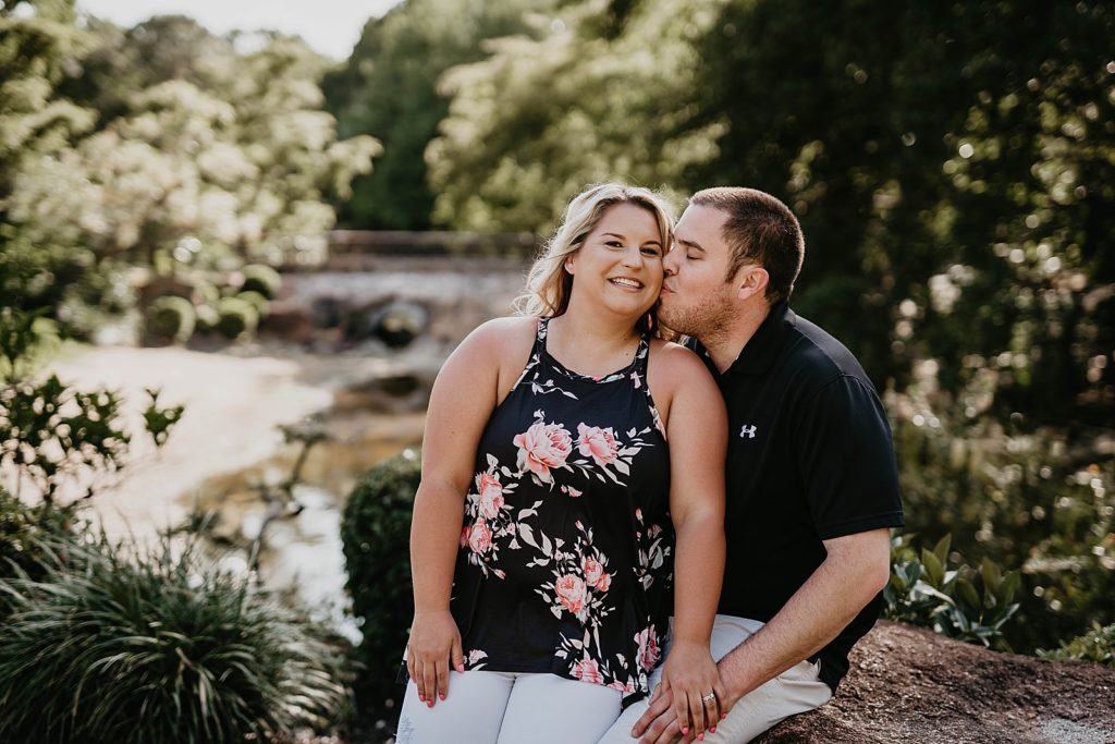 Man kissing woman on the cheek sitting on the rock