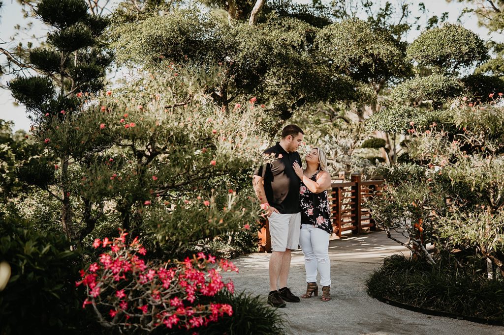 Couple holding each other by pretty greenery and flowers