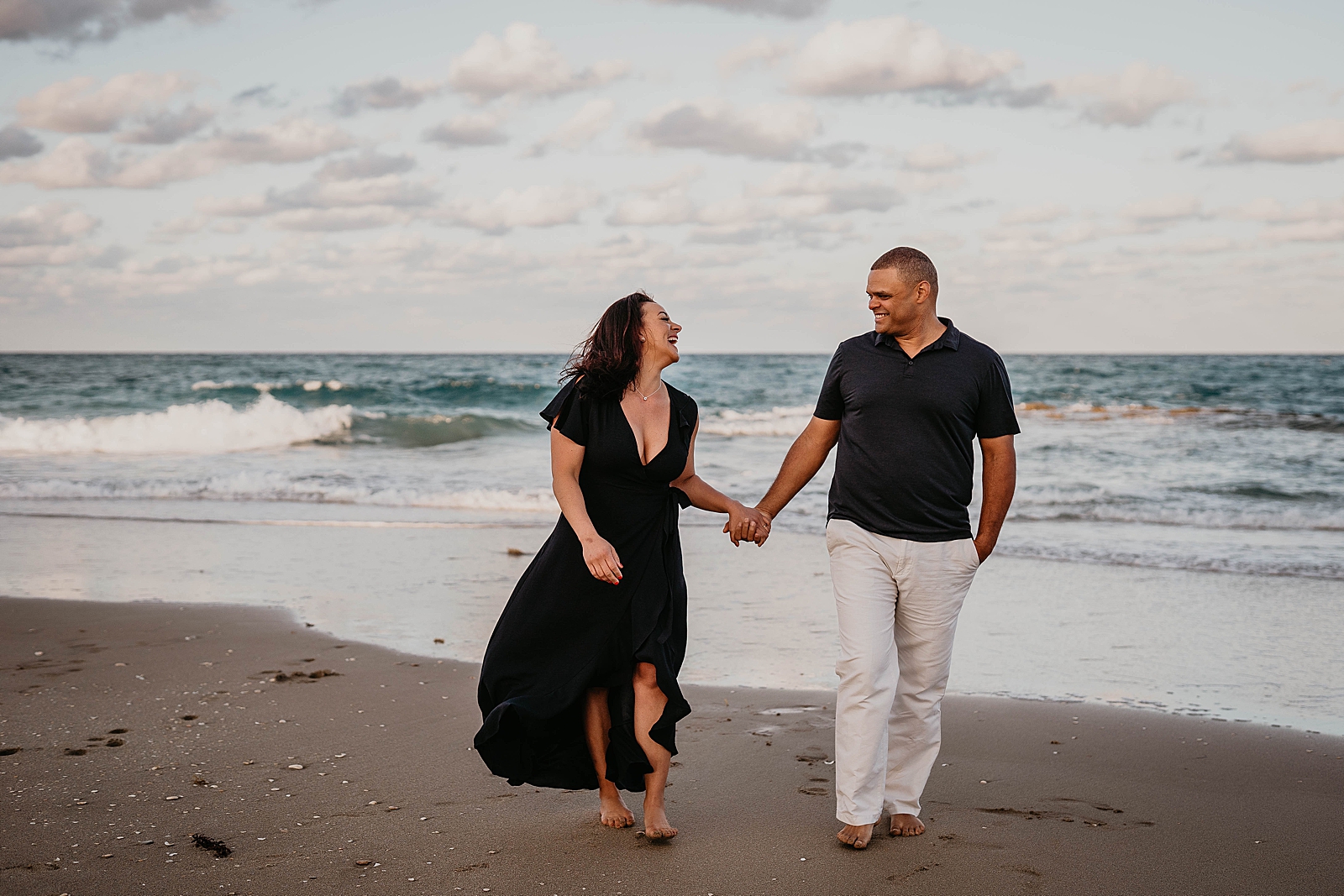 Husband and wife holding hands and walking on the sand