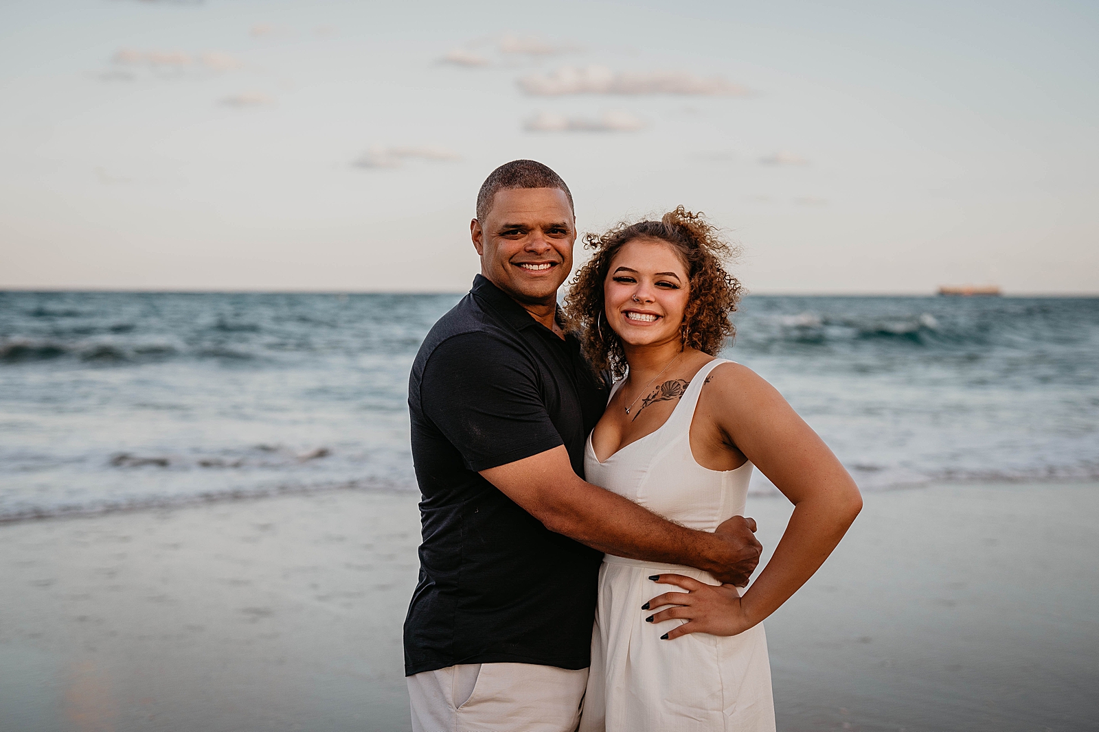Father hugging her daughter on the beach in front of the ocean