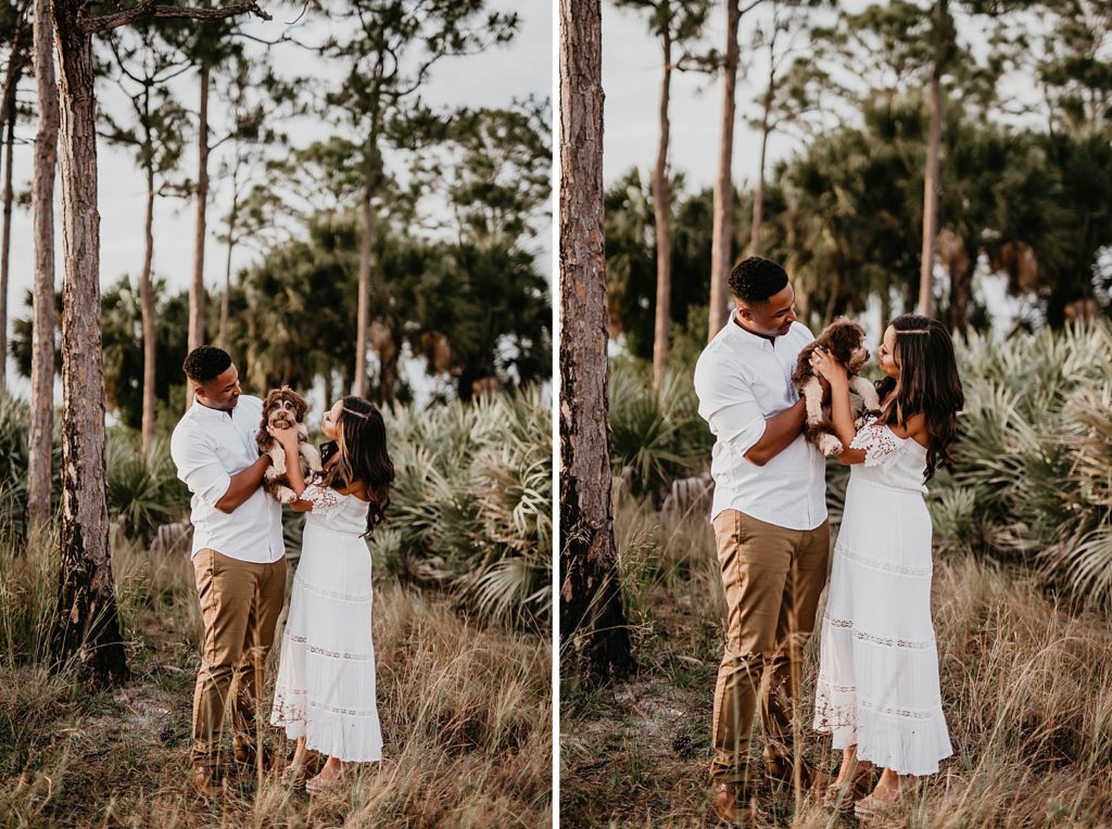 Couple holding dog together by trees