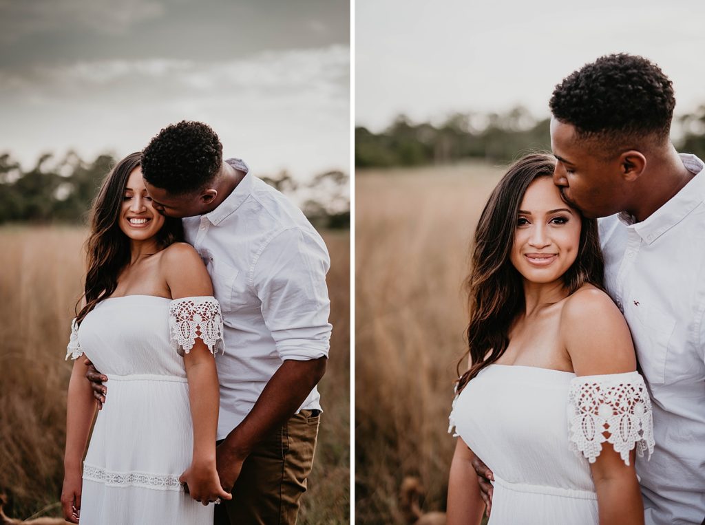 Man kissing woman on the forehead by tall grass