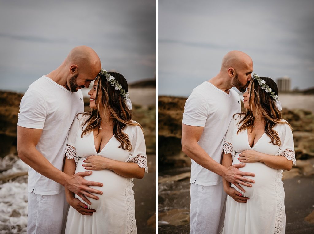 Man holding pregnant wife and kissing her on the forehead