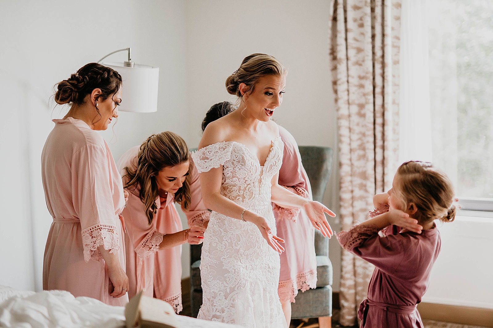 Bride getting help buttoning her wedding dress