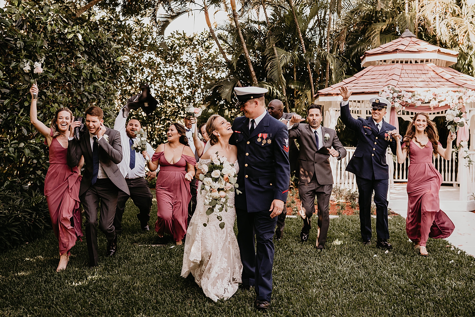 Bride and Groom holding each other with wedding party behind them having fun