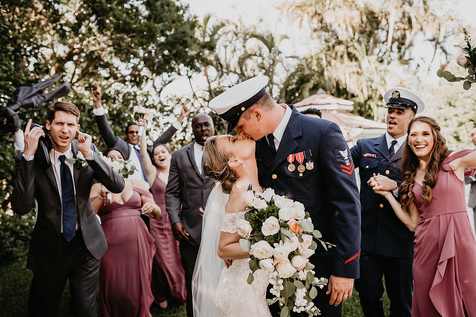 Bride and Groom kissing with wedding party behind them