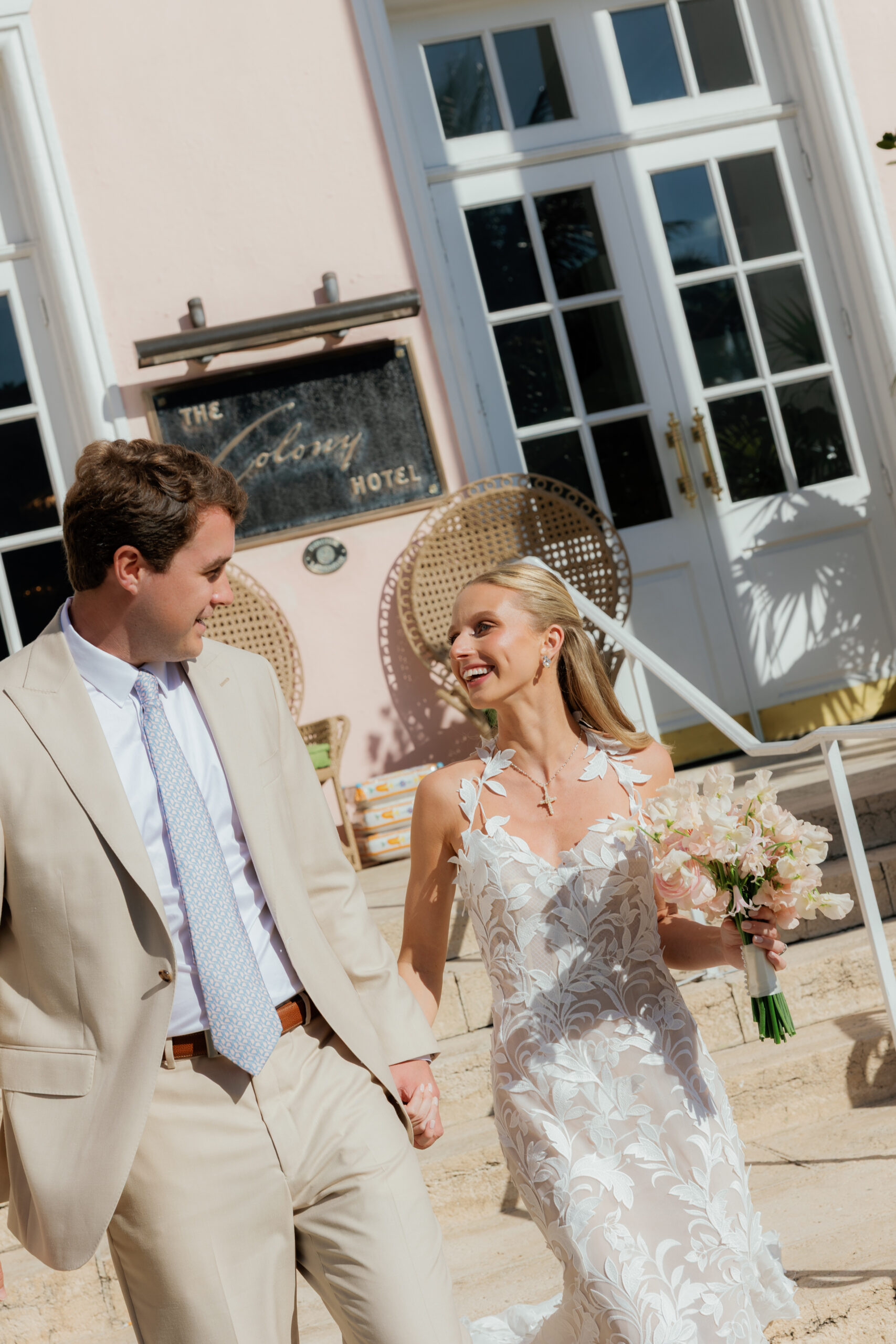 Harper and Luke wedding at The Colony Palm Beach - getting ready - A smiling bride and groom walk hand-in-hand outside The Colony Hotel.