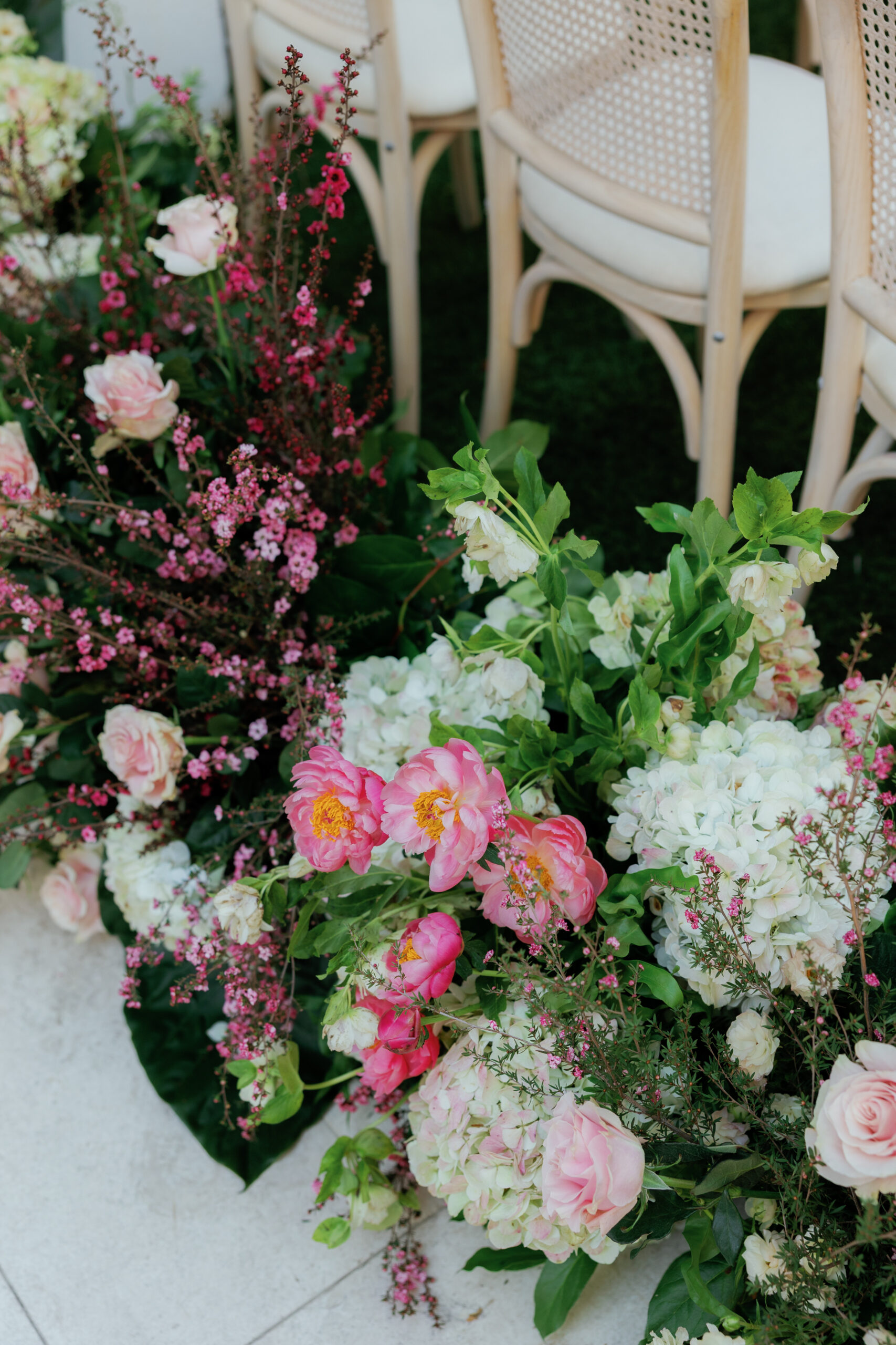 Harper and Luke wedding at The Colony Palm Beach - ceremony - A close-up of floral arrangements with pink and white flowers, and chairs in the
