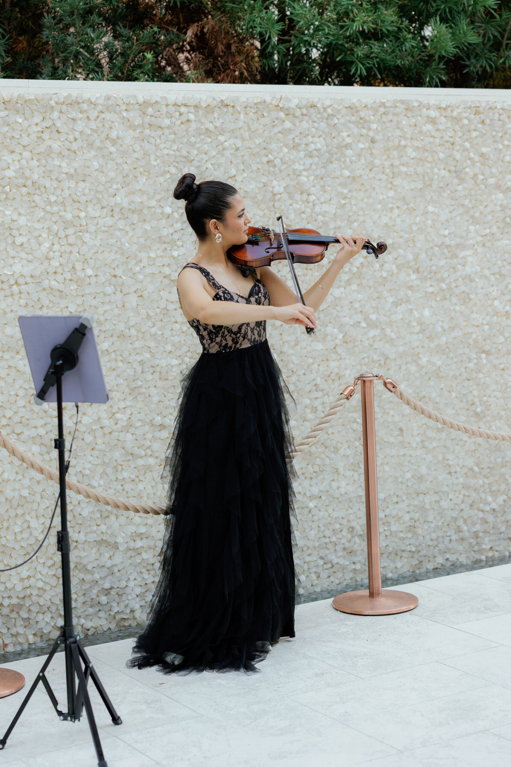 Harper and Luke wedding at The Colony Palm Beach - reception - A woman in a black dress plays the violin at a formal event.