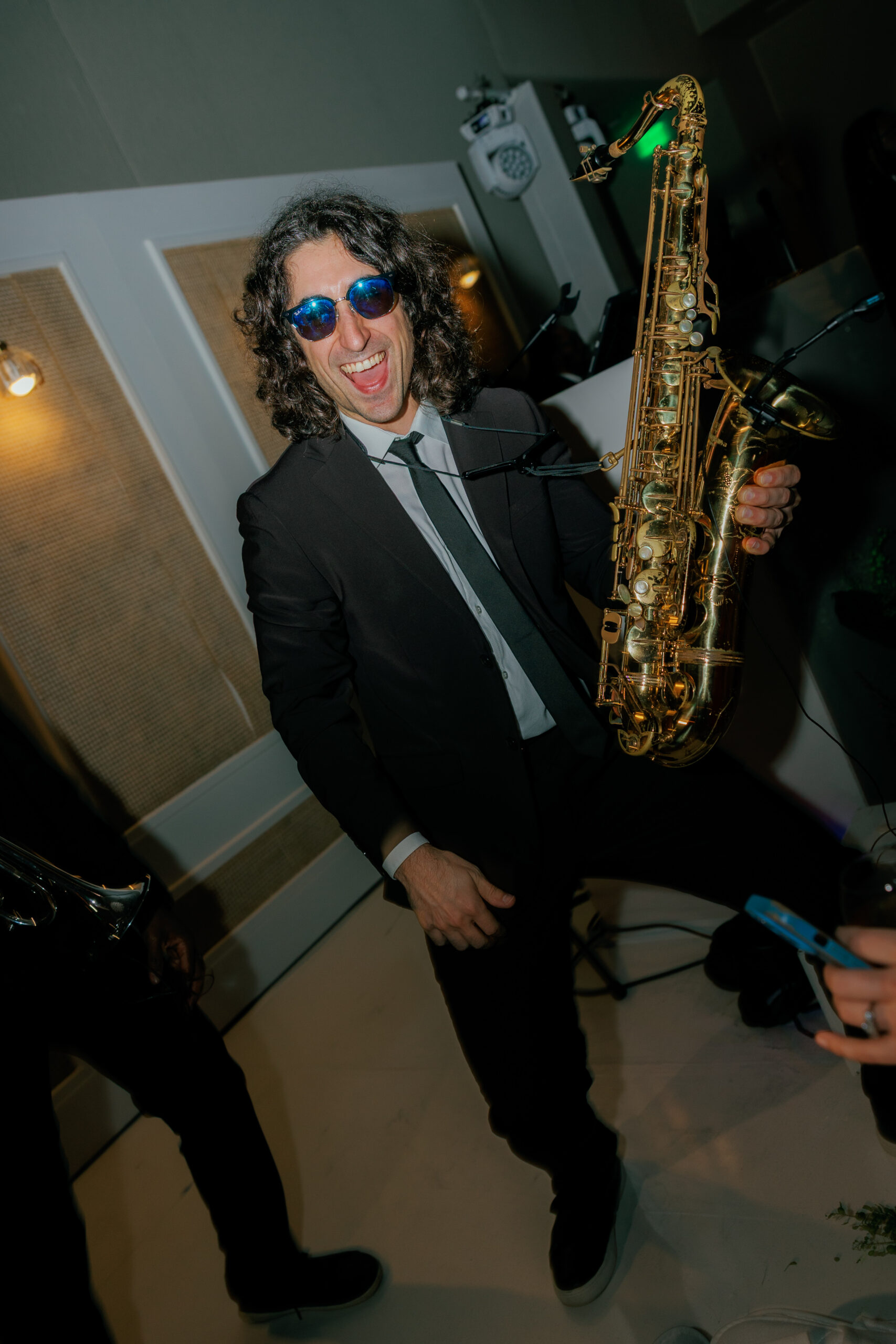 Harper and Luke wedding at The Colony Palm Beach - reception - A man in a suit and sunglasses enthusiastically plays the saxophone at a lively 