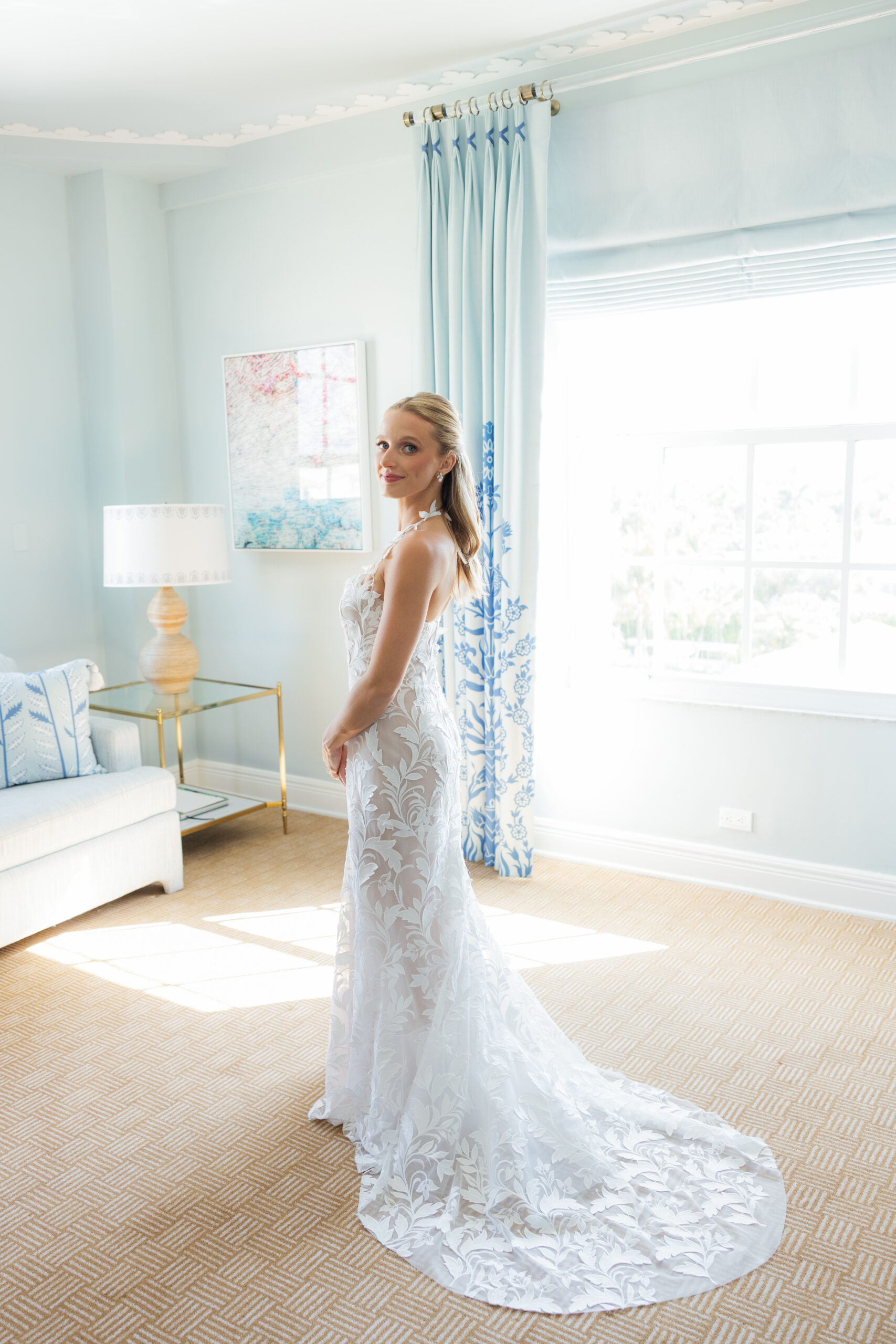 Harper and Luke wedding at The Colony Palm Beach - getting ready - A bride in a white lace wedding dress stands in a light blue room with patterned