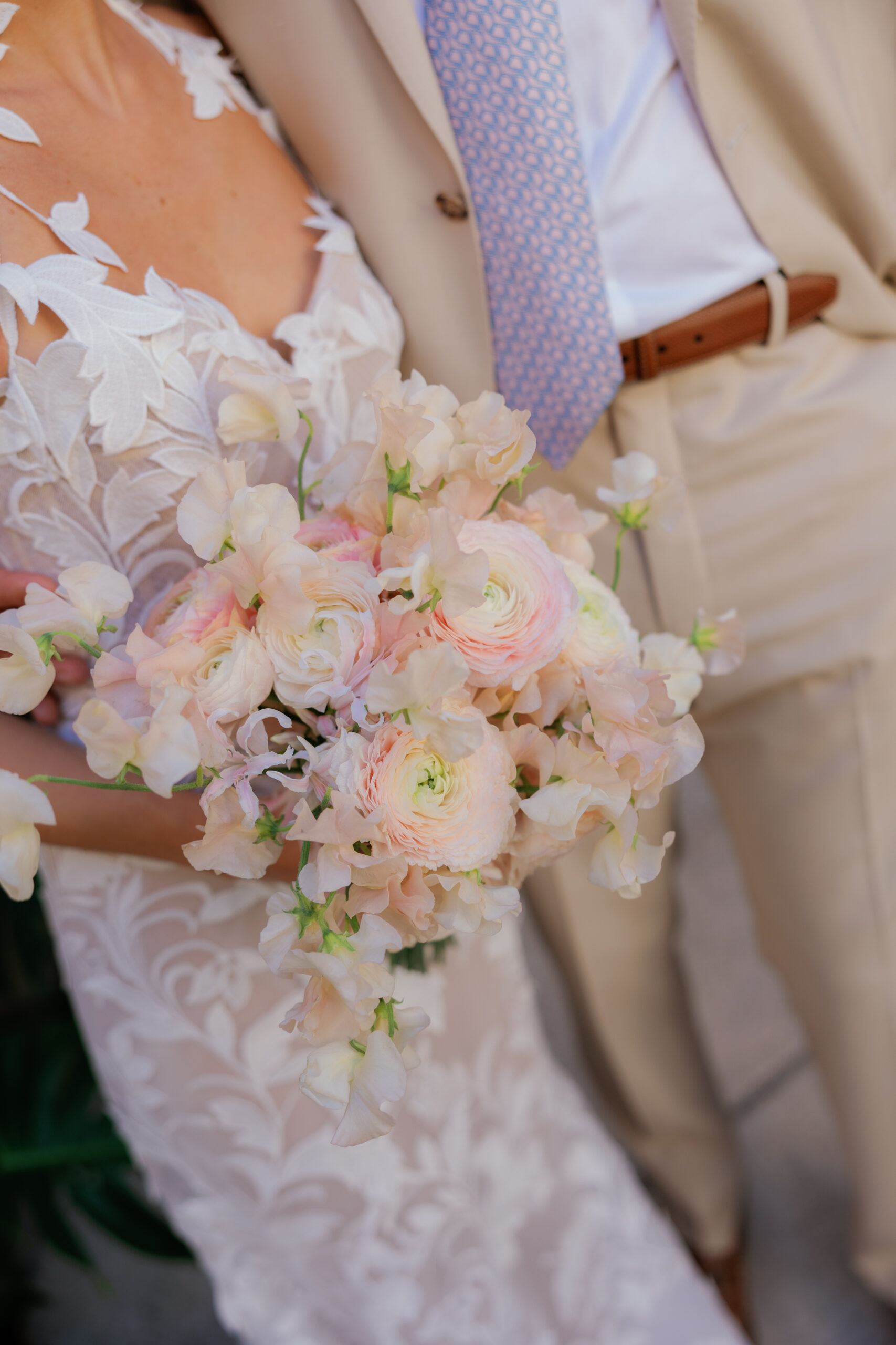 Harper and Luke wedding at The Colony Palm Beach - getting ready - A close-up of a bride in a white lace dress holding a pink and white floral bouq