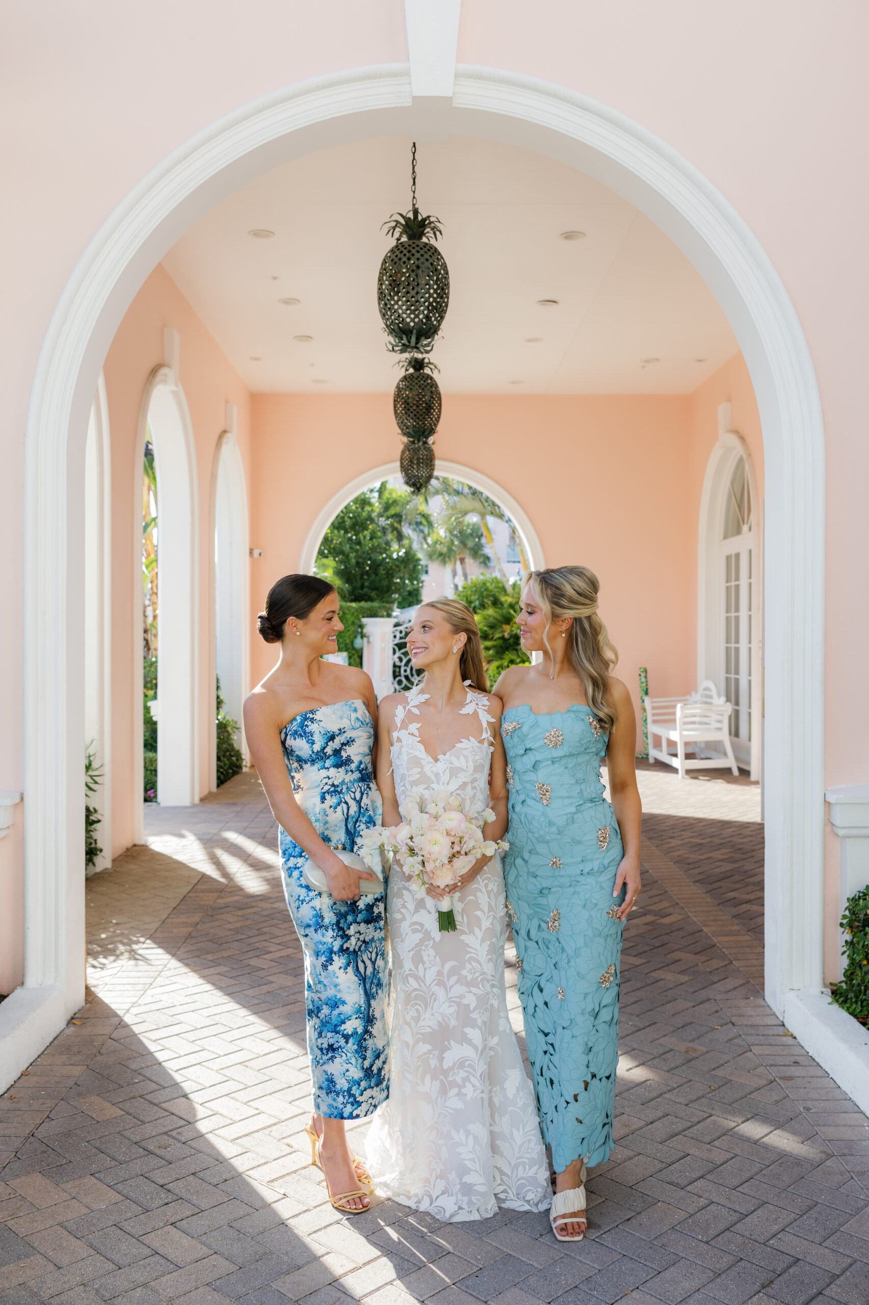 Harper and Luke wedding at The Colony Palm Beach - getting ready - The bride and two bridesmaids pose together in a beautiful outdoor arched walkwa
