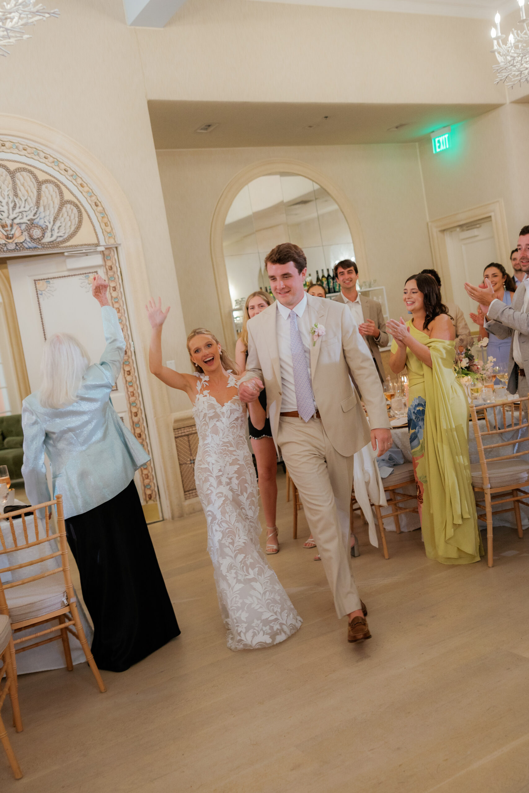 Harper and Luke wedding at The Colony Palm Beach - reception - The bride and groom enter a reception hall, smiling and waving to clapping guest