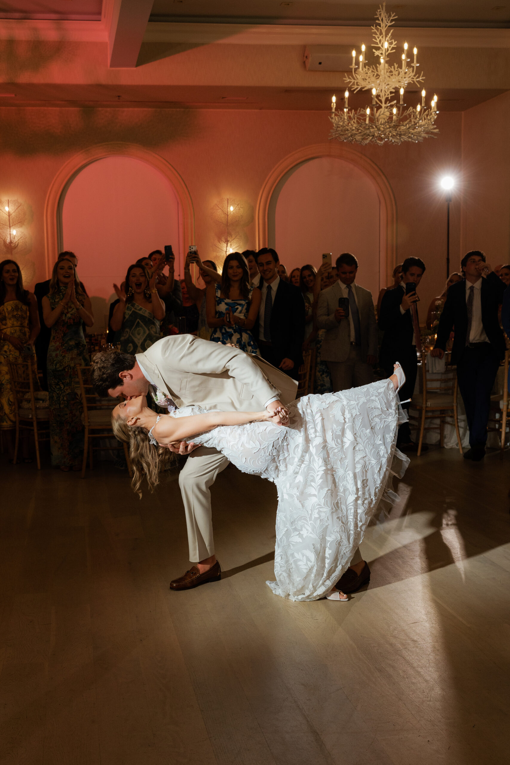 Harper and Luke wedding at The Colony Palm Beach - reception - A couple dances and kisses on the dance floor surrounded by guests.