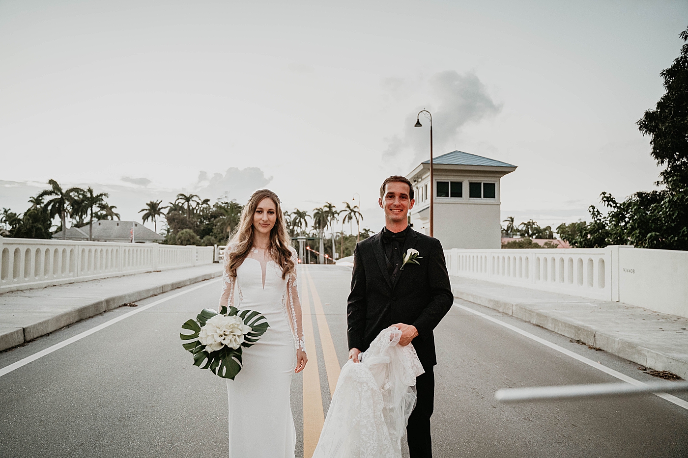 Bride and Groom on the bridge with Groom assisting with the train Waterstone Resort and Marina Wedding captured by South Florida Wedding Photographer Krystal Capone Photography