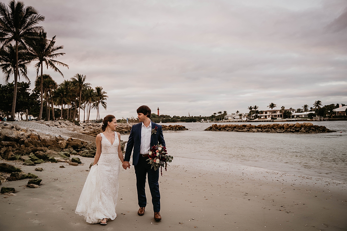 Bride and Groom holding hands by the water on the beach Out of the Blue Celebrations Wedding Photography captured by South Florida Wedding Photographer Krystal Capone Photography 