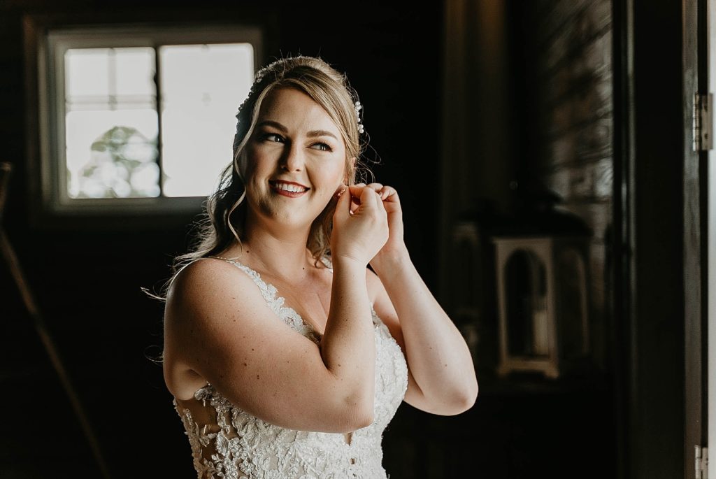 Bride getting ready putting earrings on Ever After Farms Wedding Photography captured by South Florida Wedding Photographer Krystal Capone Photography 