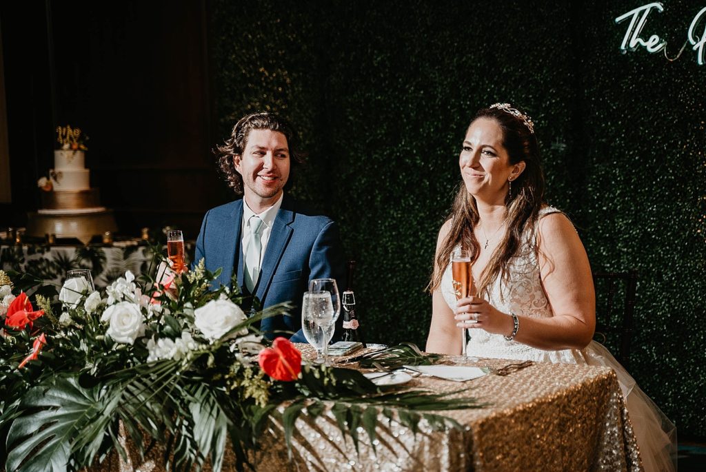Bride and Groom sitting at sweetheart table Jupiter Beach Resort Wedding Photography captured by South Florida Wedding Photographer Krystal Capone Photography 