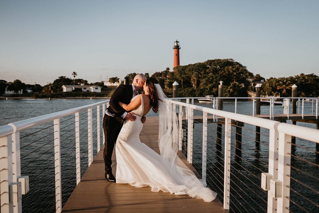 Bride and Groom kissing on the dock with the lighthouse in sight Pelican Club Wedding Photography captured by South Florida Wedding Photographer Krystal Capone Photography 