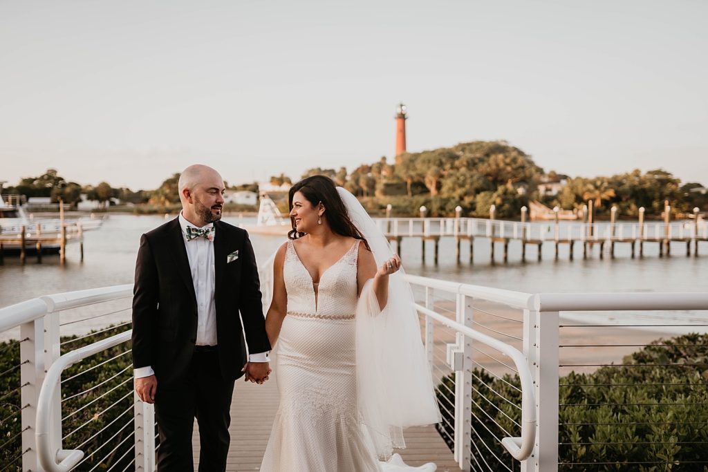 Bride and Groom holding hands walking together on the dock Pelican Club Wedding Photography captured by South Florida Wedding Photographer Krystal Capone Photography 