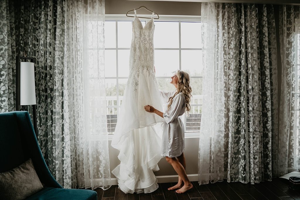 Bride looking at hung up Wedding Dress before Getting Ready Pelican Club Wedding Photography captured by South Florida Wedding Photographer Krystal Capone Photography