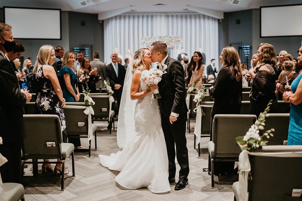 Bride and Groom kissing halfway down the aisle Pelican Club Wedding Photography captured by South Florida Wedding Photographer Krystal Capone Photography