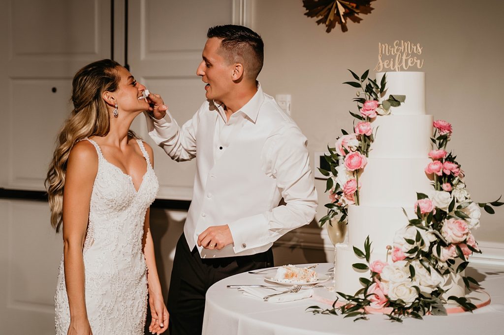 Groom giving messy bite to Bride at Reception Pelican Club Wedding Photography captured by South Florida Wedding Photographer Krystal Capone Photography