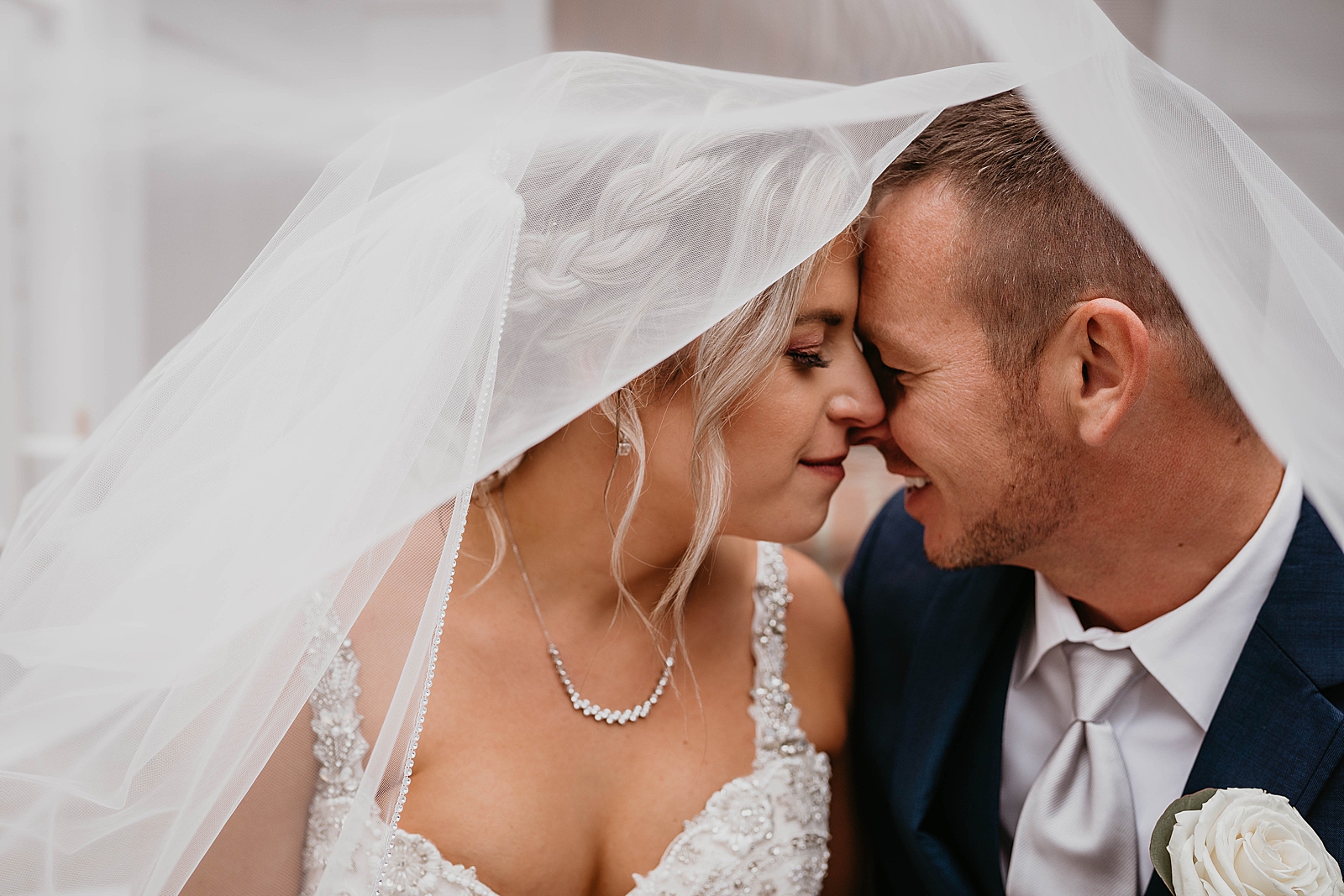 Couple nuzzling under the veil