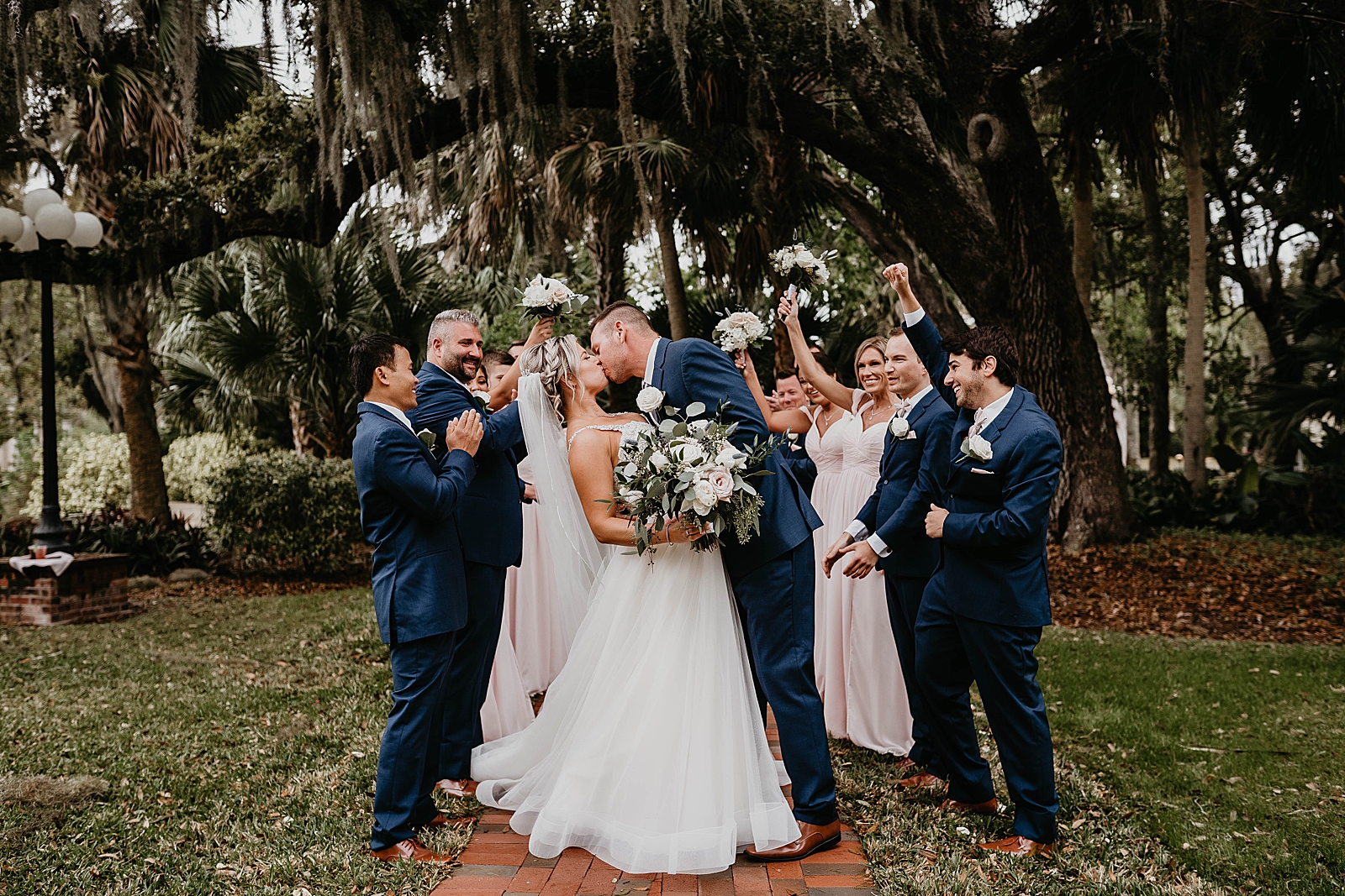 Bride and Groom kissing with wedding party around them