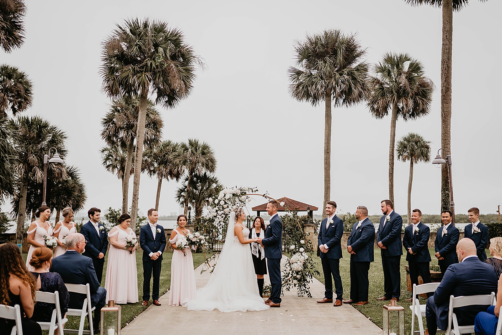 Bride and Groom holding hands with wedding party watching for Ceremony